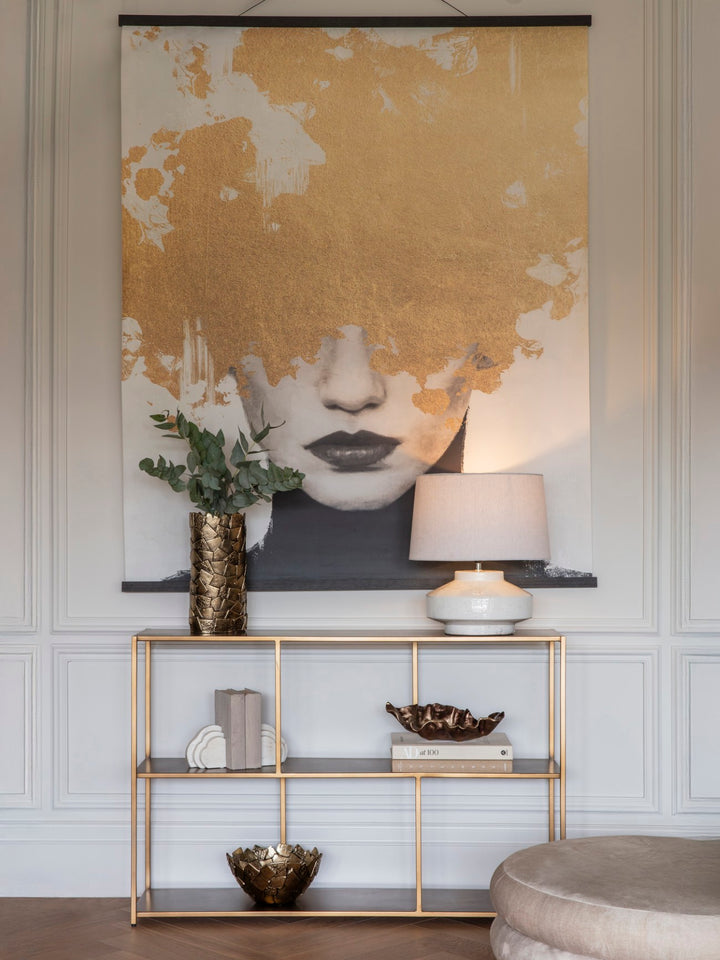 Modern interior with a gold and black abstract wall art piece, a gold console table, and decorative items.