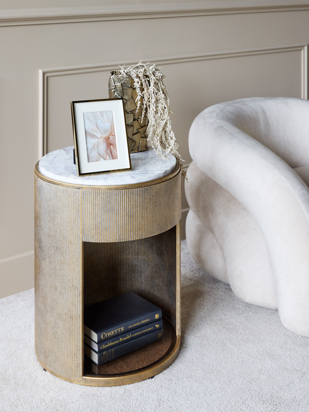 Round side table with marble top and books in a room setting