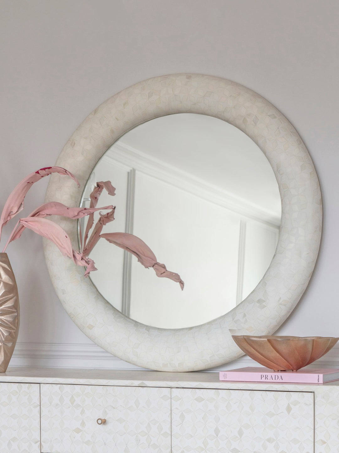 Round marble mirror on a white surface with decorative elements