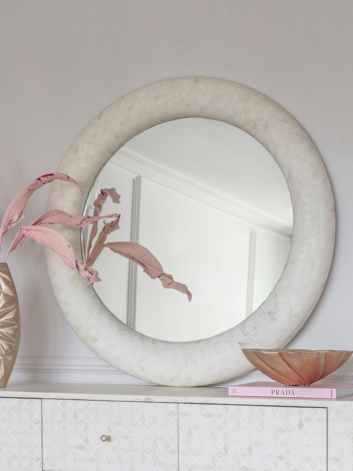 Round marble mirror on a white surface with decorative elements
