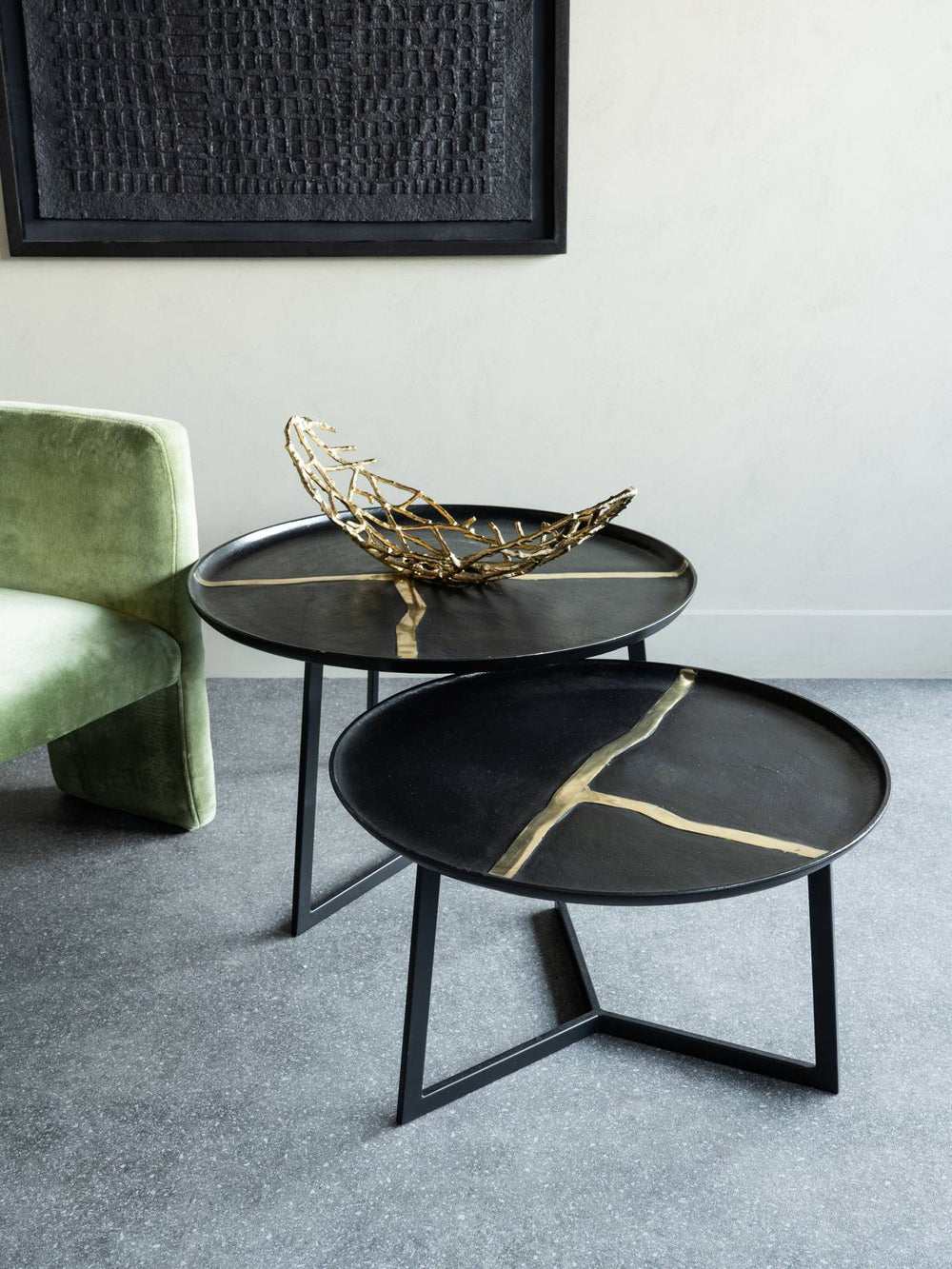Two black side tables with gold accents in a modern living room setting.
