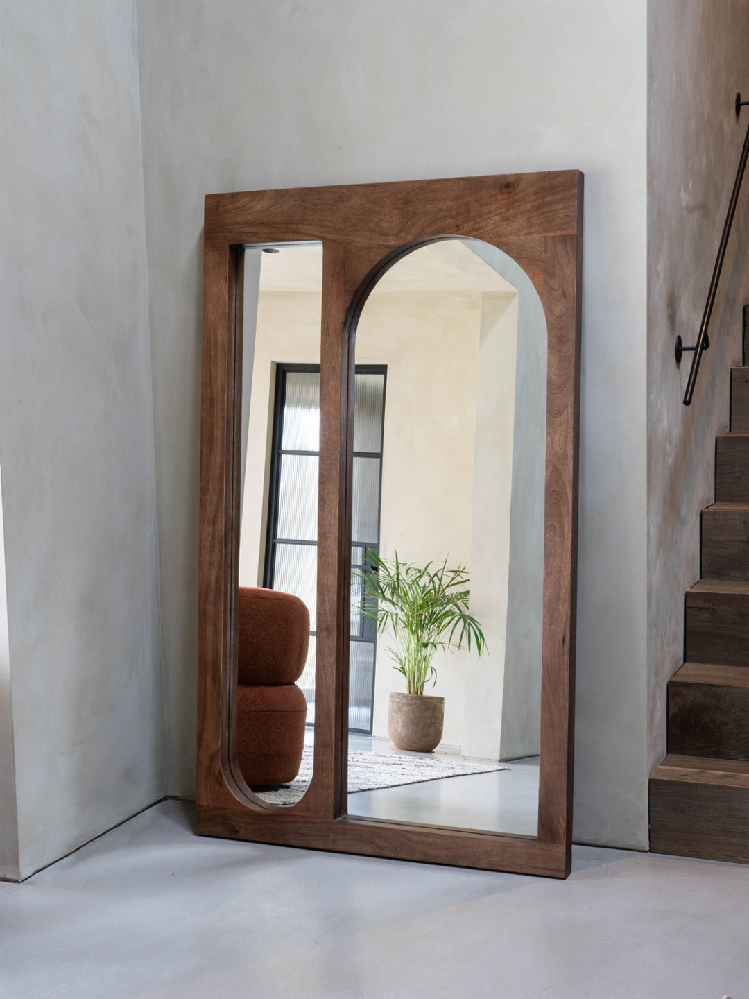 Wooden-framed mirror leaning against a wall with a neutral background