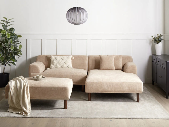 Beige sectional sofa in a modern living room with a plant and side table.