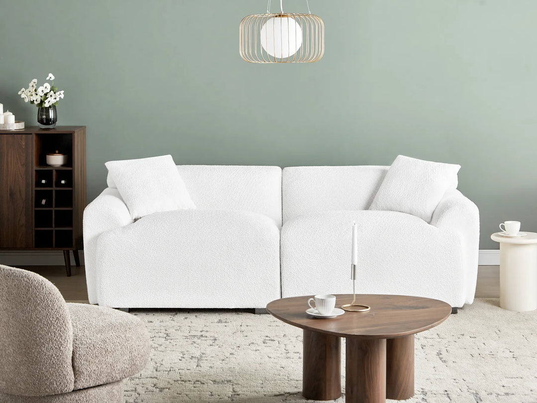 Modern living room with a white sofa, wooden coffee table, and decorative items.