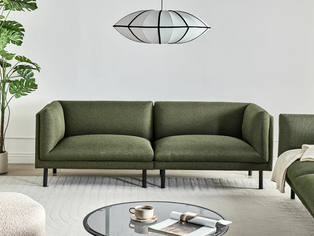 Green sofa in a modern living room with a plant and coffee table.