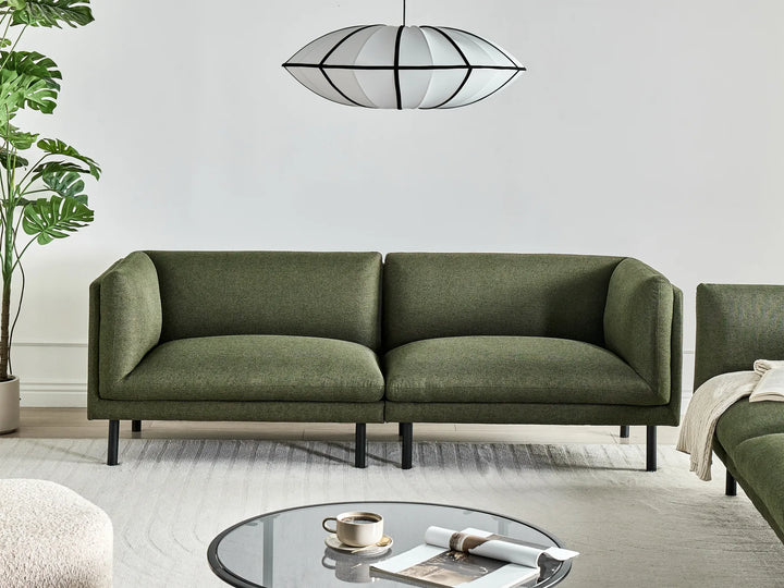 Green sofa in a modern living room with a plant and coffee table.