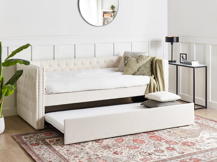 White sofa bed in a room with a mirror and small table.