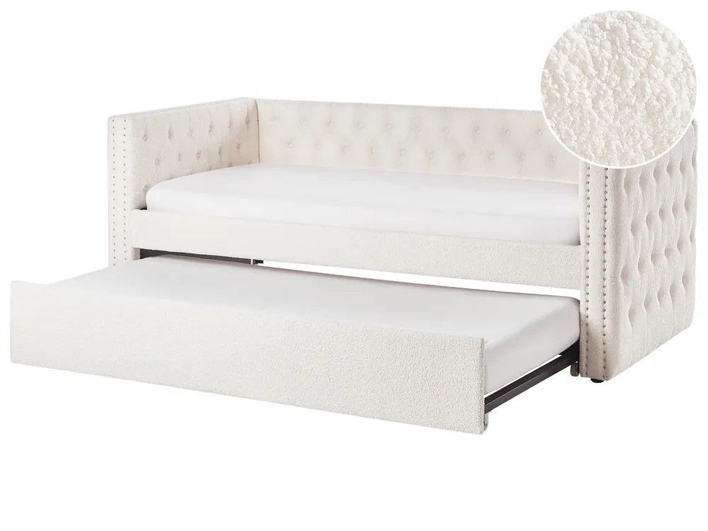 White upholstered bed with tufted design and pull-out trundle on a white background.