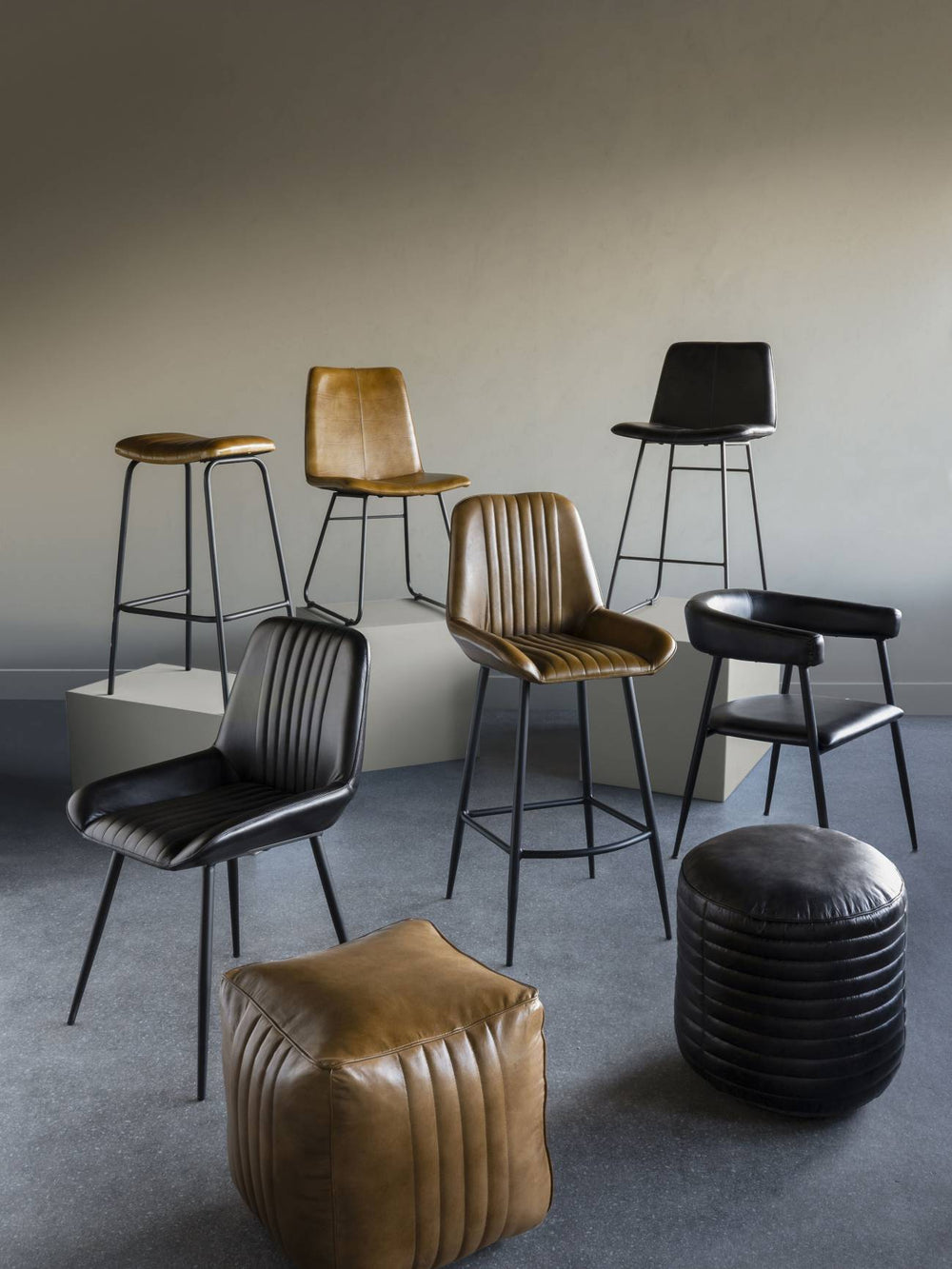 Set of modern bar stools and a pouf in a minimalistic room.