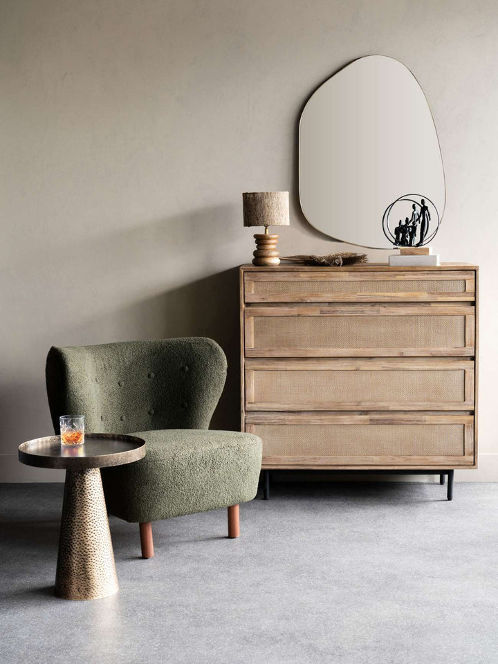 Modern interior with a green armchair, wooden side table, and dresser.
