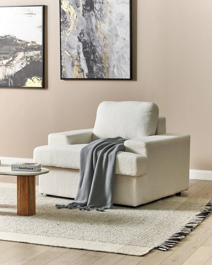 Modern living room with a beige armchair, coffee table, and abstract art on the wall.