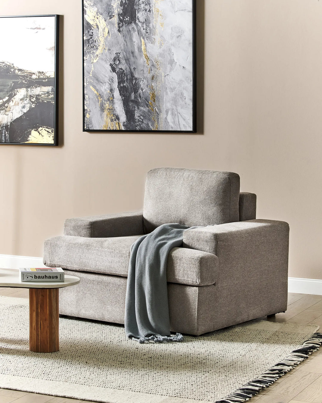 Gray armchair with a blanket in a living room setting with abstract art on the wall.