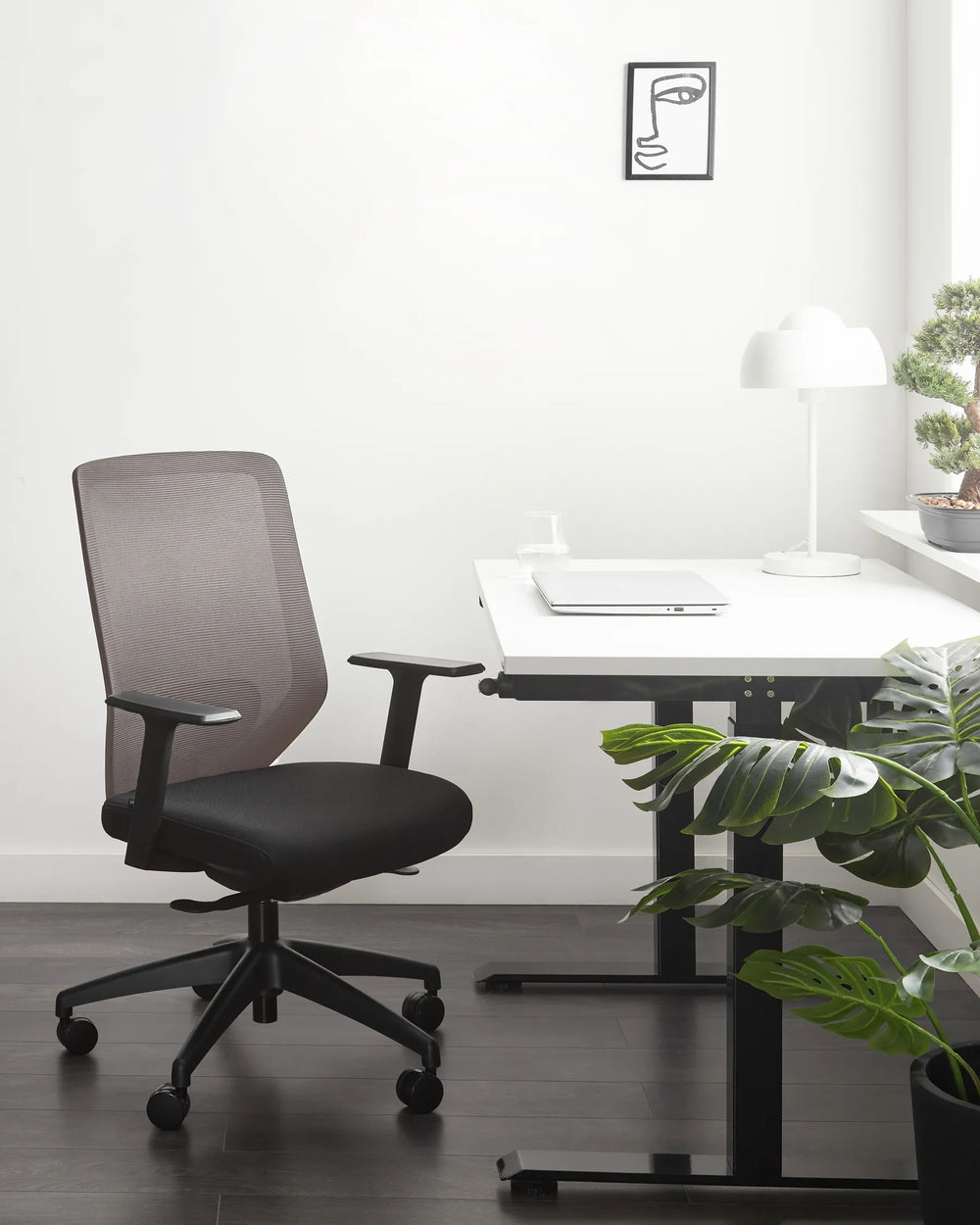 Modern office setup with a black mesh office chair and white desk.