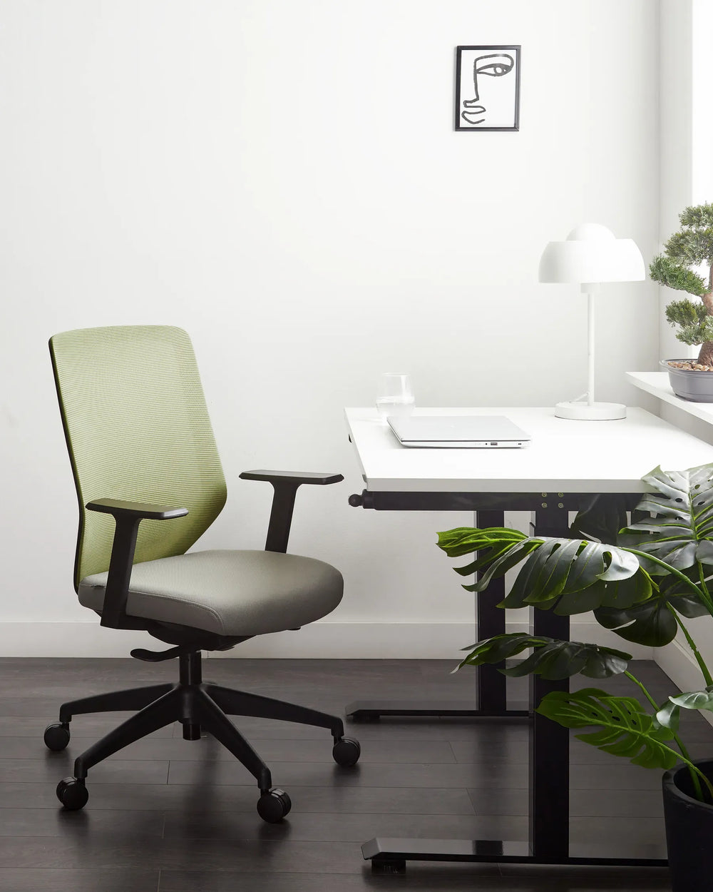 Modern office chair in front of a desk with a plant and lamp in a minimalistic room.