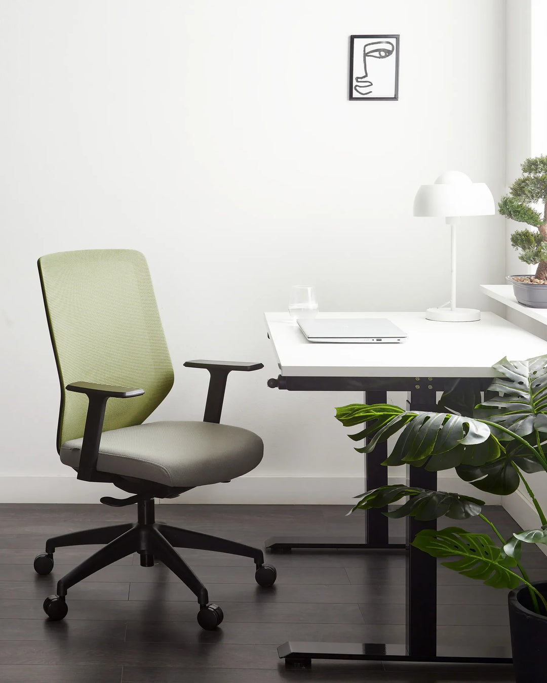 Modern office chair in front of a desk with a plant and lamp in a minimalistic room.