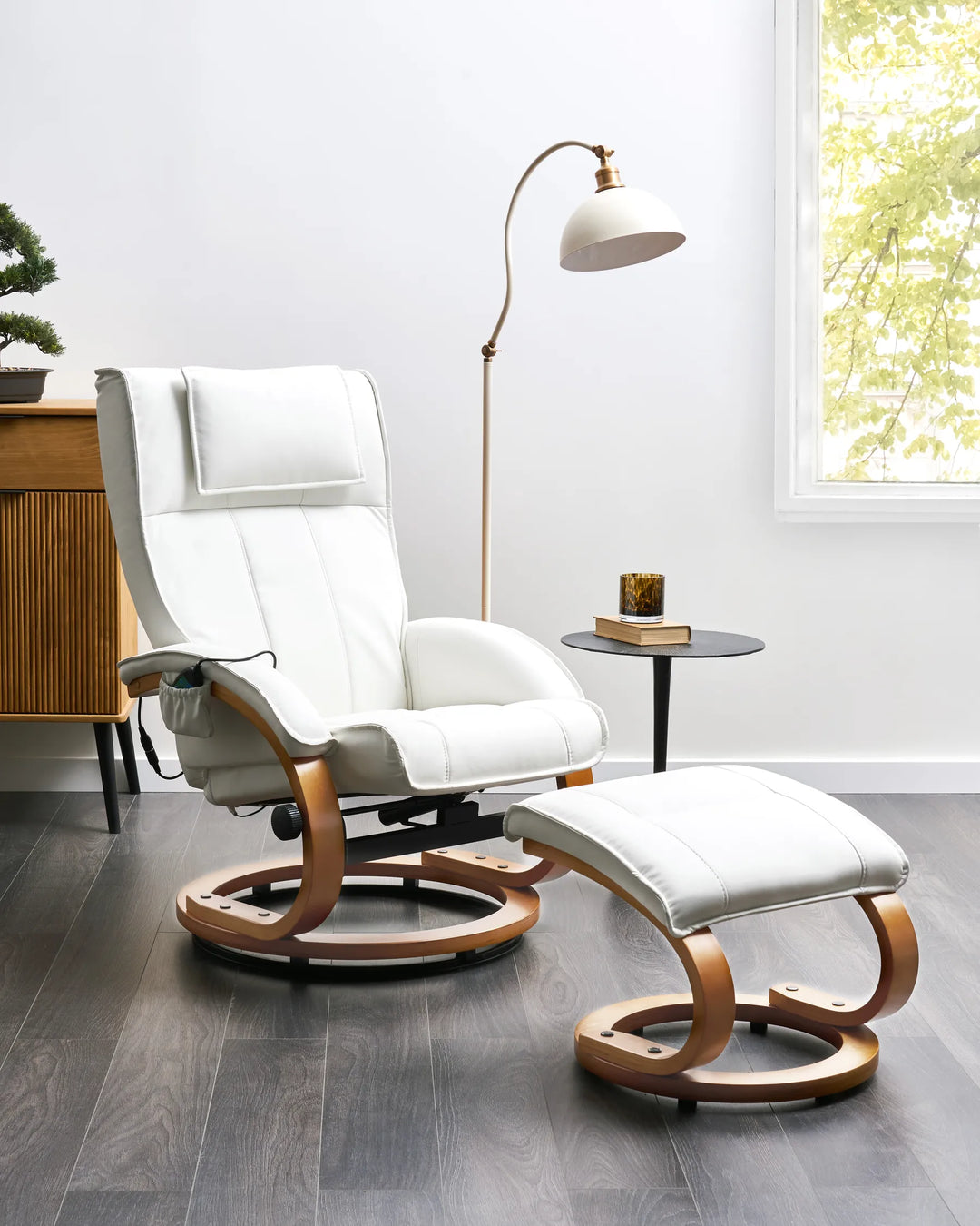 White recliner chair with wooden legs in a modern room with a lamp and small table.