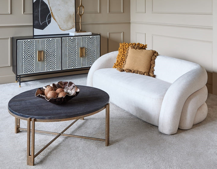 Modern living room with a white sofa, round coffee table, and decorative wall art.