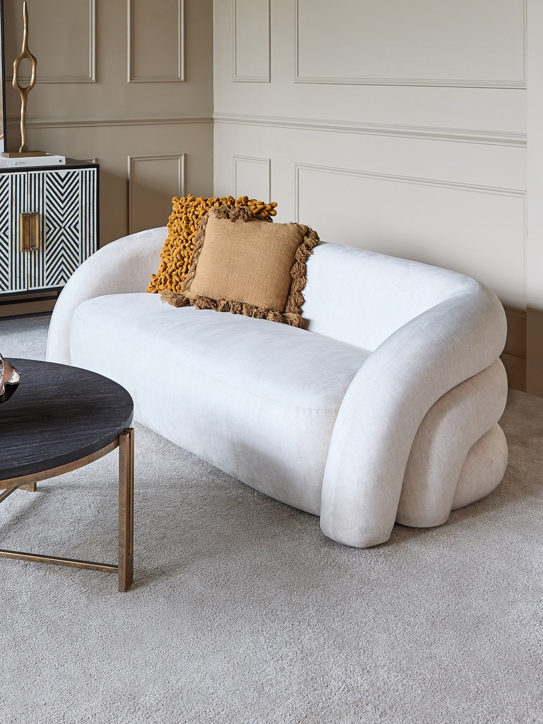 Modern white sofa with decorative pillows in a stylish living room.