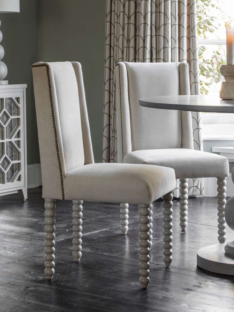 Two upholstered chairs with spindle legs in a dining room setting.