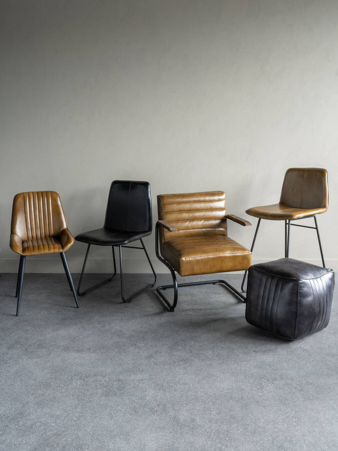 Modern furniture set with leather chairs and a table against a plain wall.