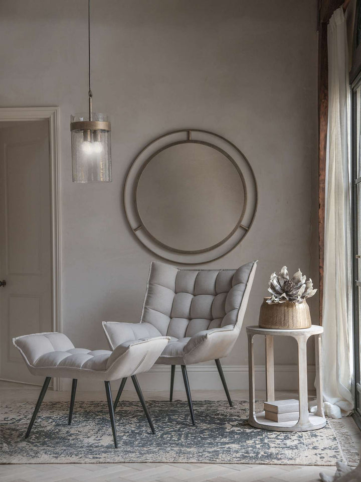 Modern interior with a gray chair, round mirror, and side table.