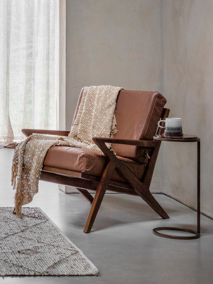 Brown leather armchair with a blanket in a minimalistic room.