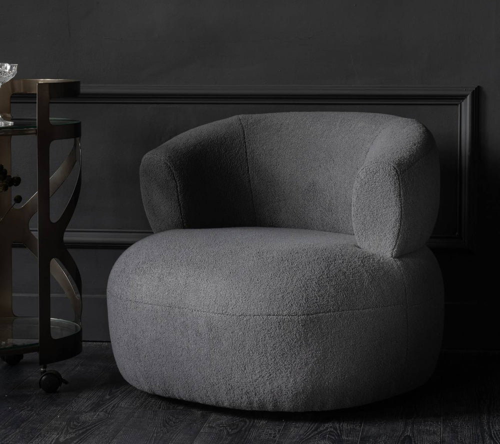 Gray armchair in a dark room with a framed black and white photo on the wall.