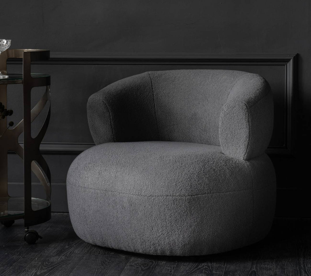 Gray armchair in a dark room with a framed black and white photo on the wall.