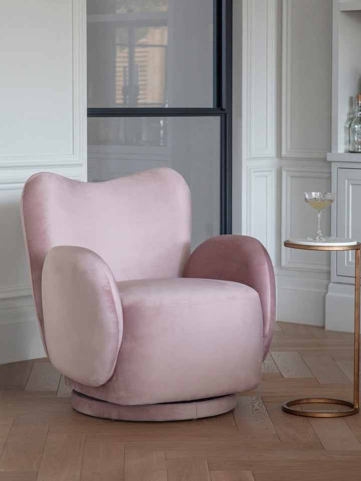 Pink armchair in a stylish room with a side table and decor.
