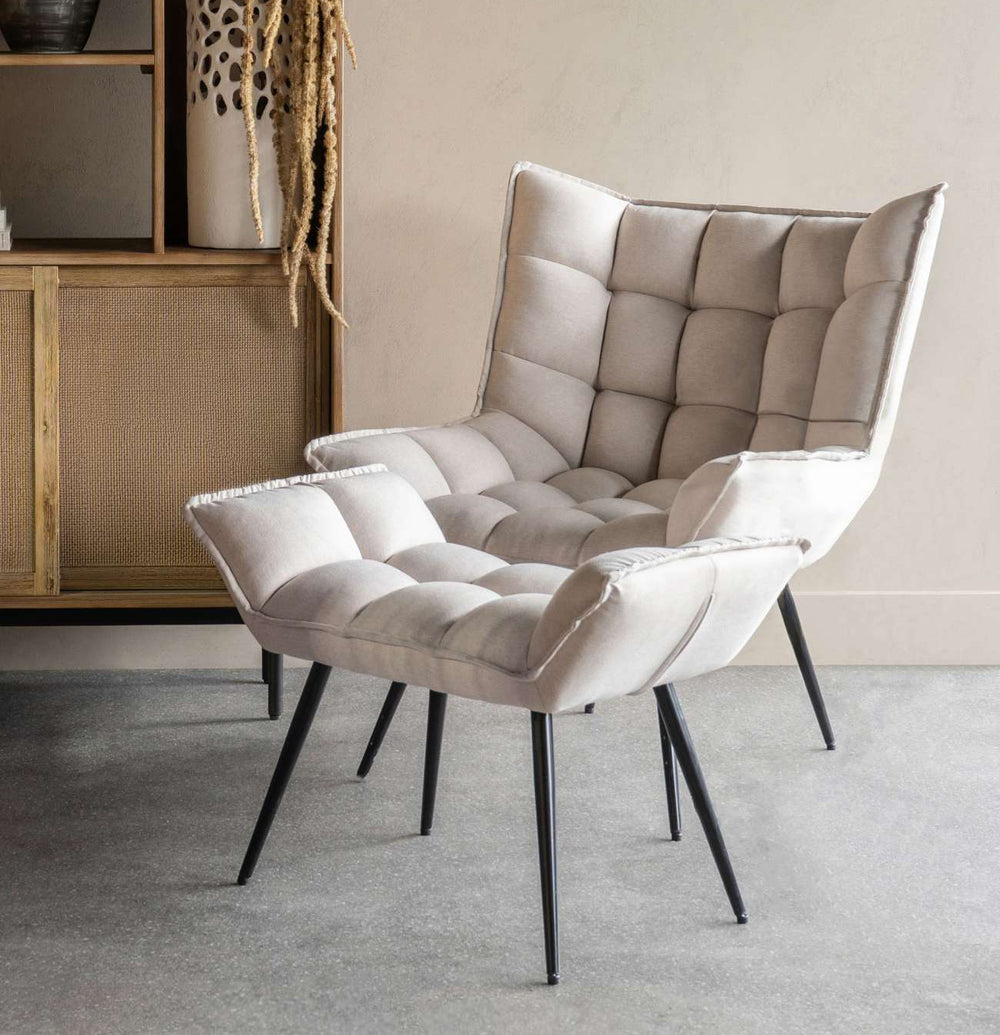 Beige armchair with quilted design in a room with a wooden shelf and decorative items.