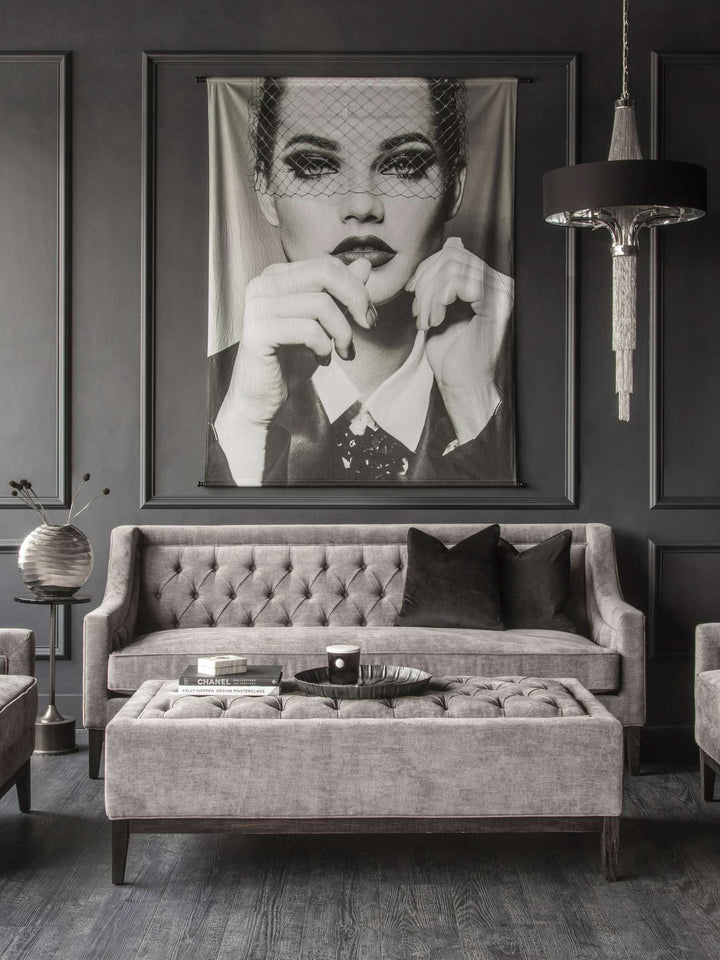 Gray tufted sofa in a room with a large framed portrait above it.