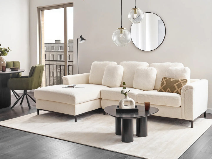 Modern living room with a white sectional sofa, coffee table, and decorative items.