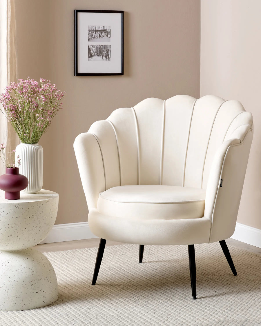 White armchair in a room with a side table and decorative elements.