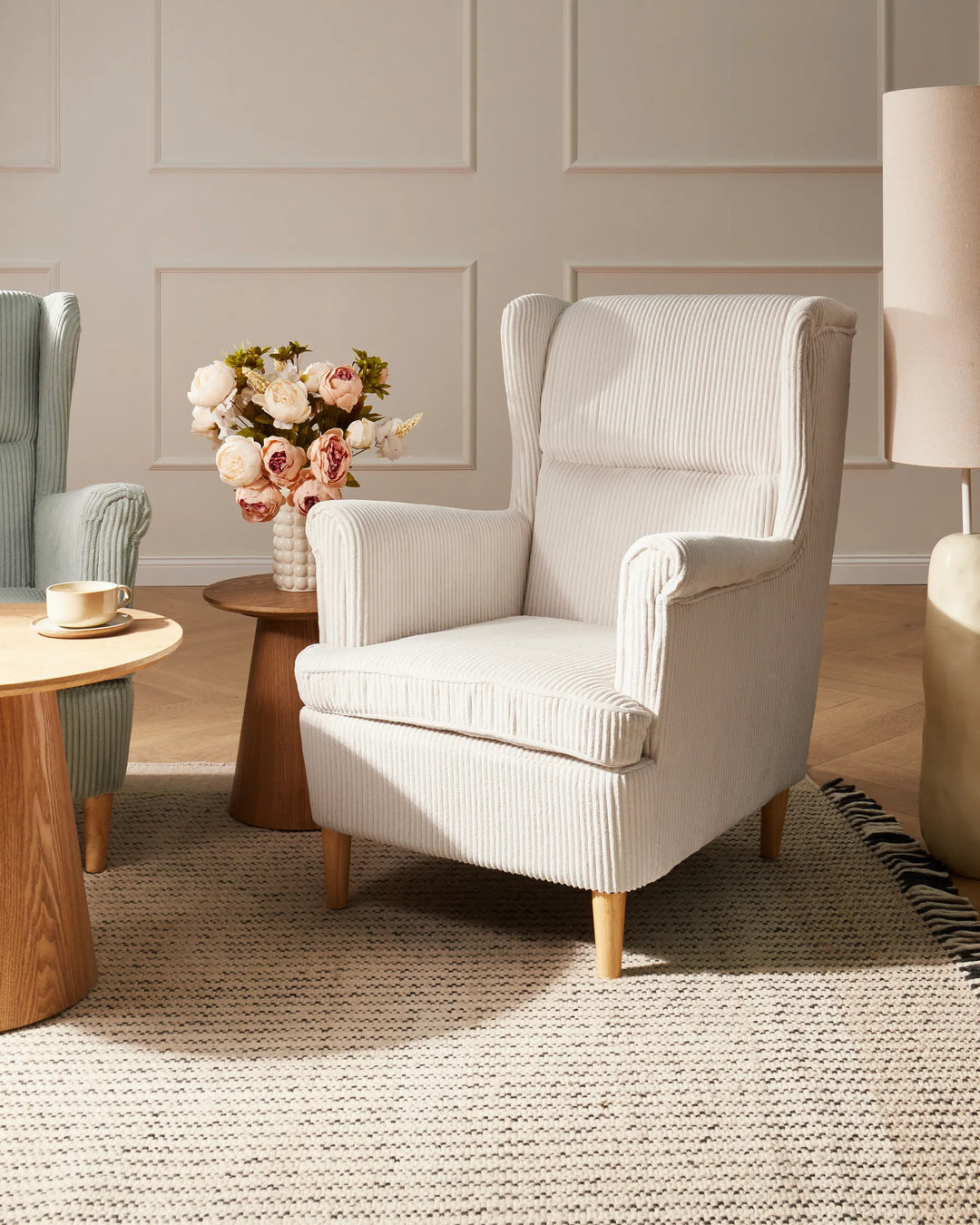 White armchair in a living room setting with a small table and flowers.
