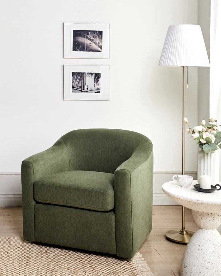 Green armchair in a living room setting with a lamp and table in the background.