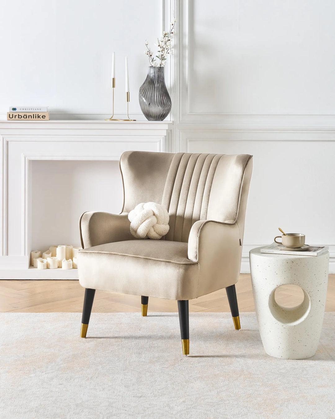 Beige armchair in a modern living room with a white wall and decorative items.
