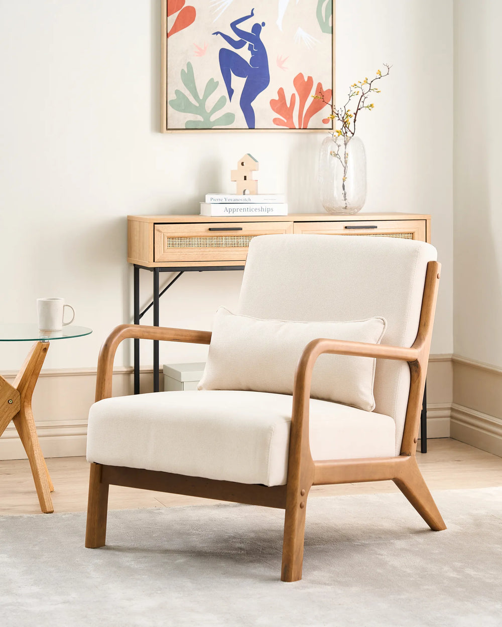 White armchair with wooden frame in a room with a small table and decorative wall art.