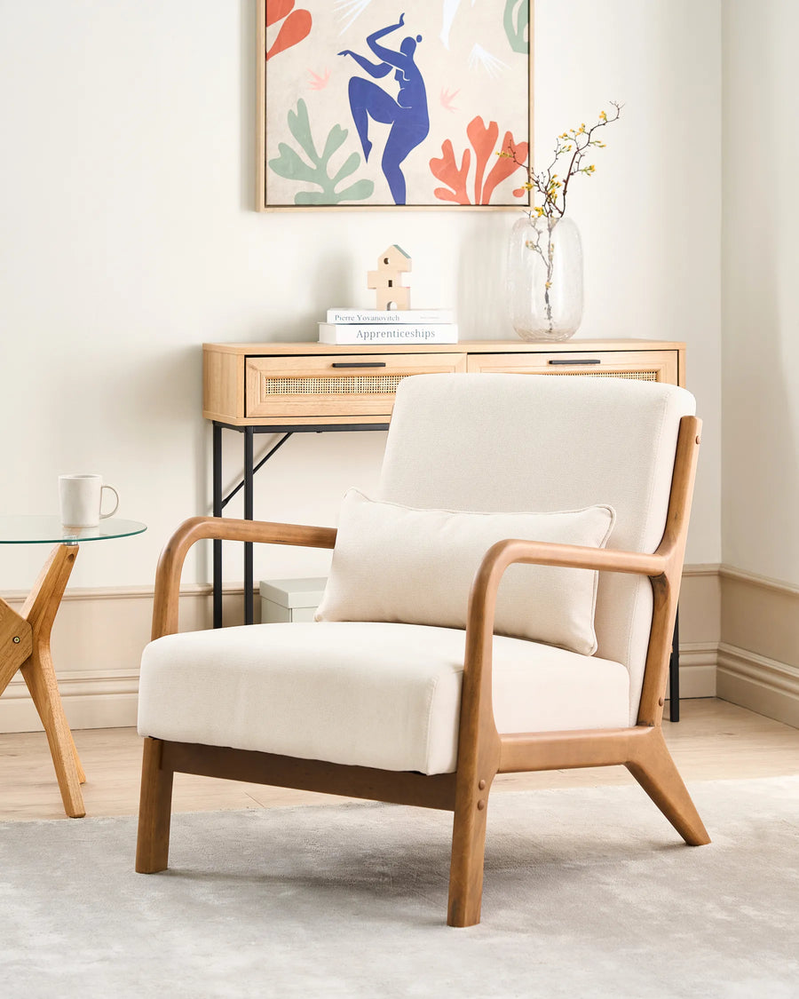 White armchair with wooden frame in a room with a small table and decorative wall art.