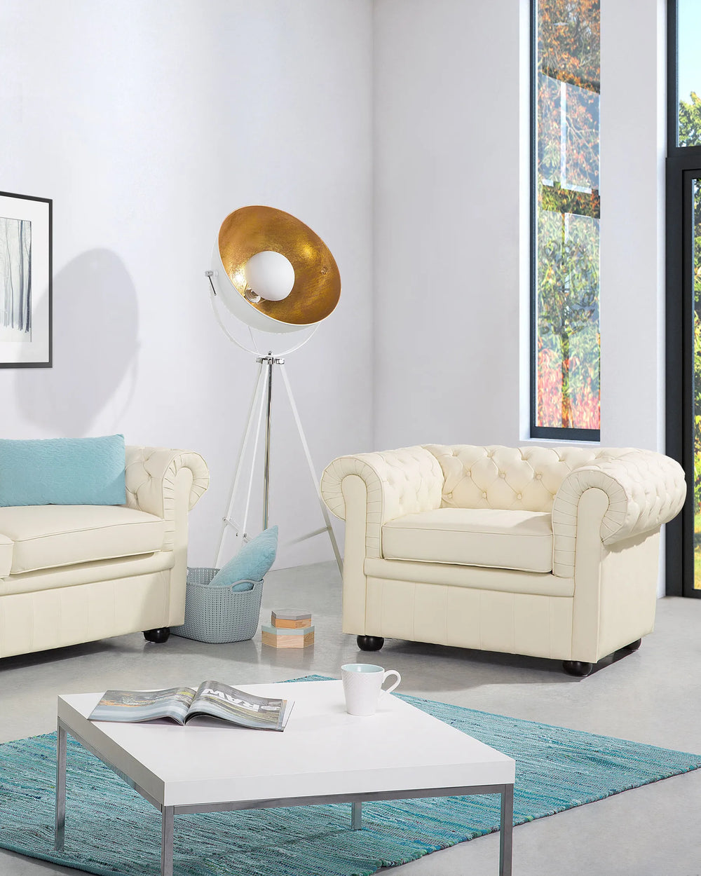 Modern living room with cream-colored sofa and armchair, white coffee table, and decorative elements.