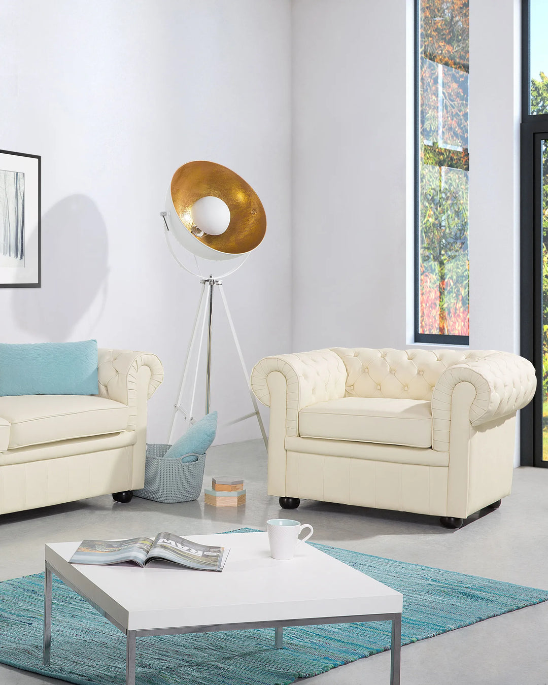 Modern living room with cream-colored sofa and armchair, white coffee table, and decorative elements.