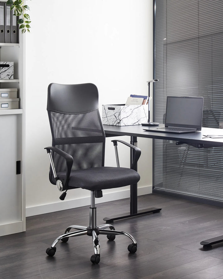 Black office chair in front of a desk with a laptop in an office setting.