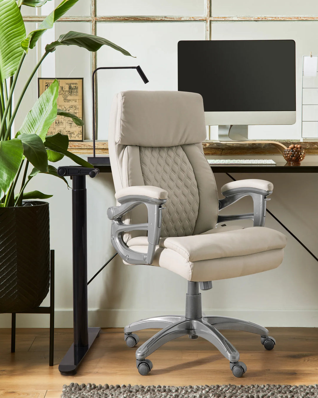 Beige office chair in a home office setting with a computer monitor and plant.