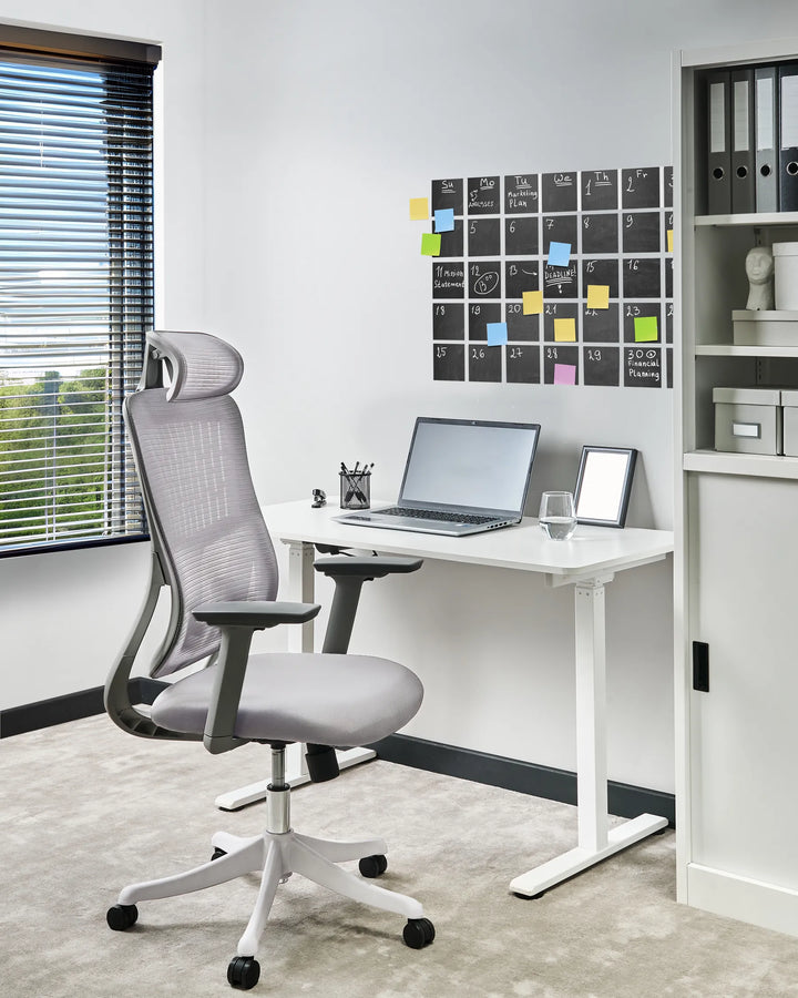 Modern office setup with a gray ergonomic chair, white desk, and a window view.