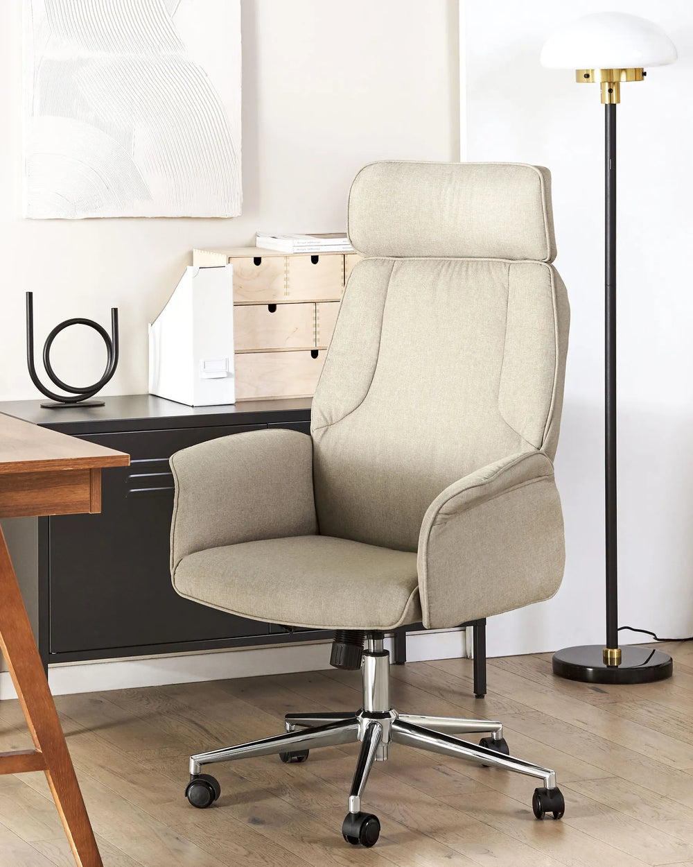 Beige office chair in a home office setting with a desk and lamp.
