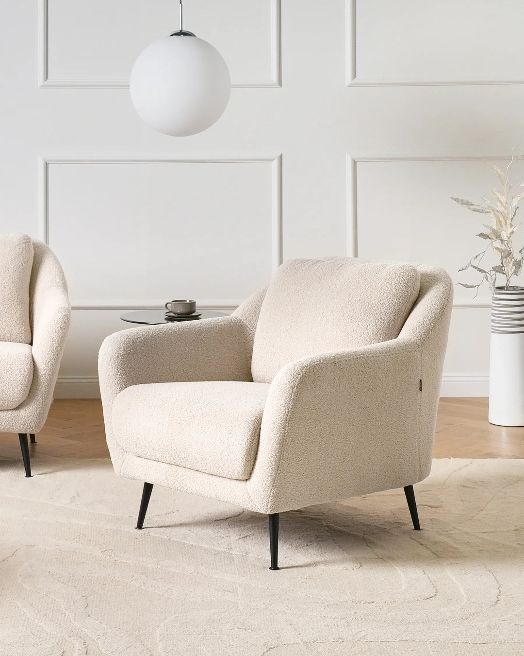 Beige armchair in a modern living room with a white wall and decorative elements.