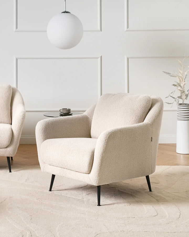 Beige armchair in a modern living room with a white wall and decorative elements.