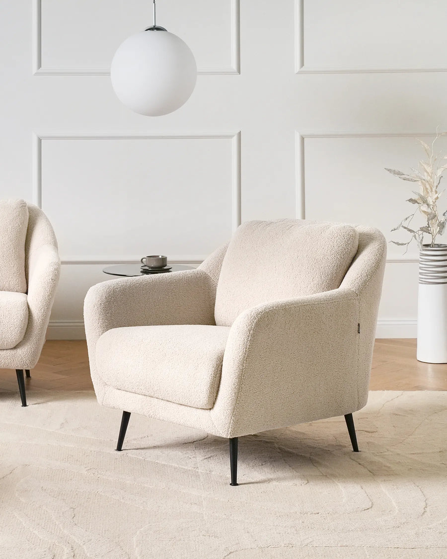 Beige armchair in a modern living room with a white wall and decorative elements.