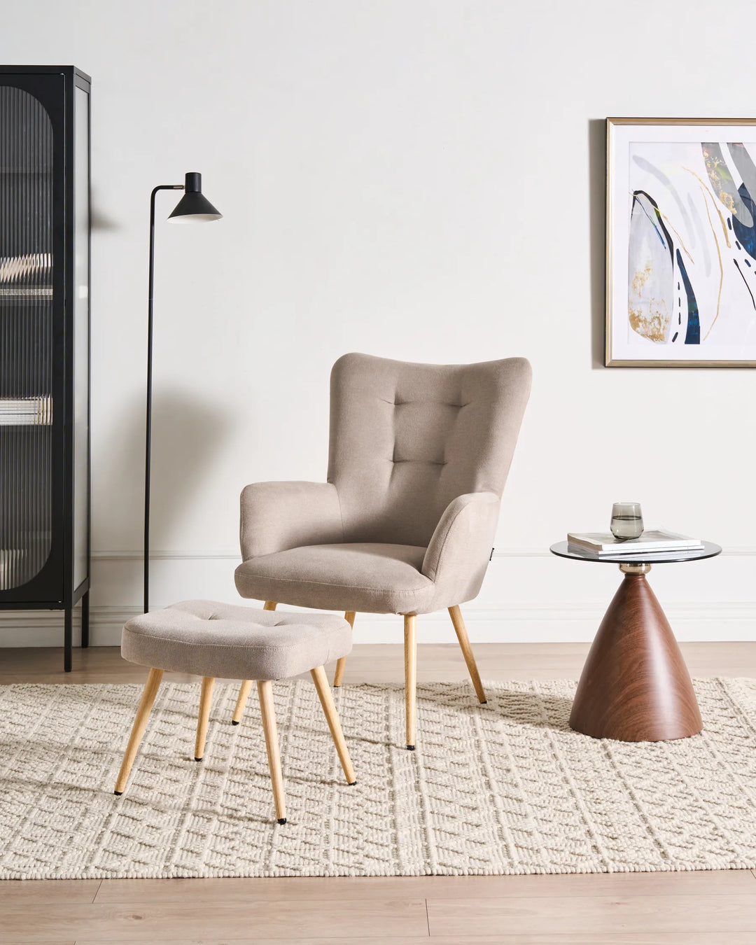 Beige armchair and ottoman in a modern living room with a side table and artwork.