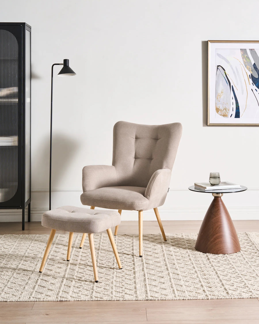 Beige armchair and ottoman in a modern living room with a side table and artwork.
