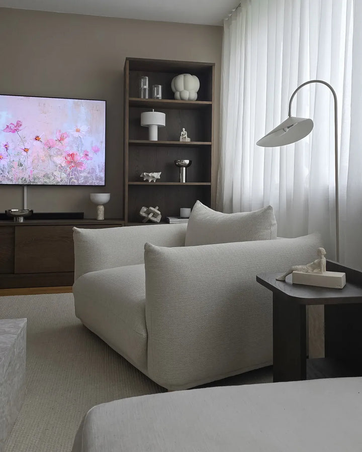 Modern living room with a gray sofa, TV, and decorative shelves.